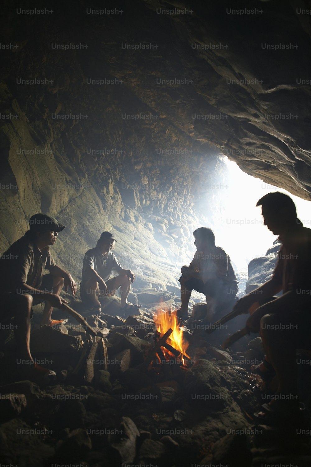 a group of people sitting around a fire in a cave