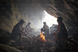 Eine Gruppe von Menschen, die um ein Feuer in einer Höhle sitzen