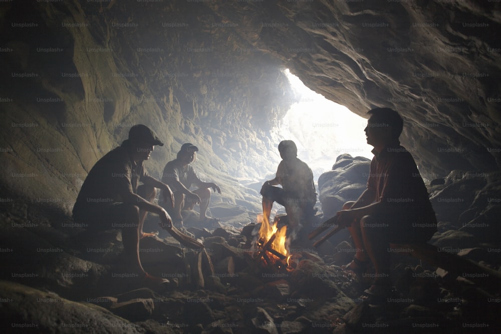 a group of people sitting around a fire in a cave