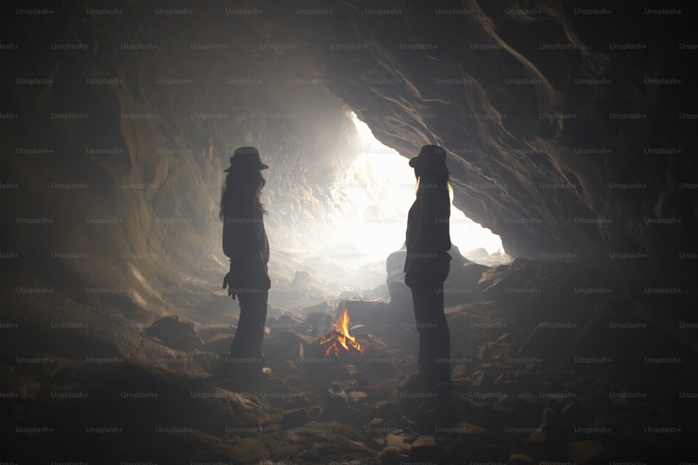 two people standing in front of a fire in a cave