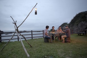 a group of people sitting around a table on top of a grass covered field