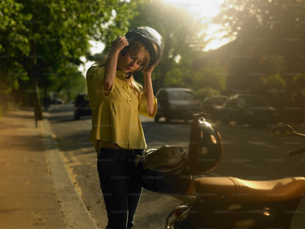 Une femme en chemise jaune se tient à côté d’une moto