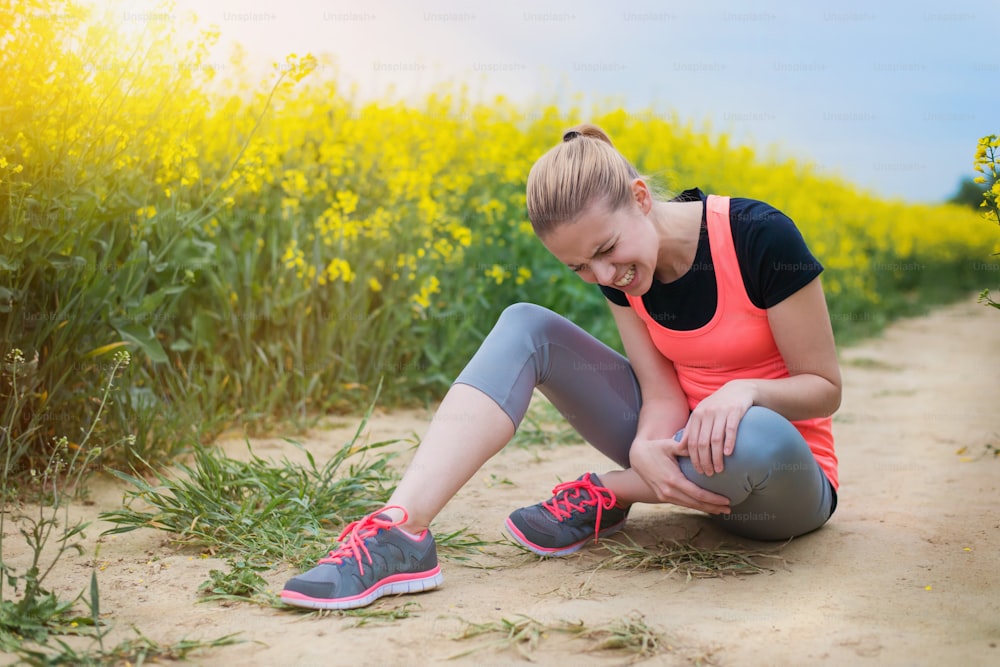 Young runner having an accident outside in spring canola field