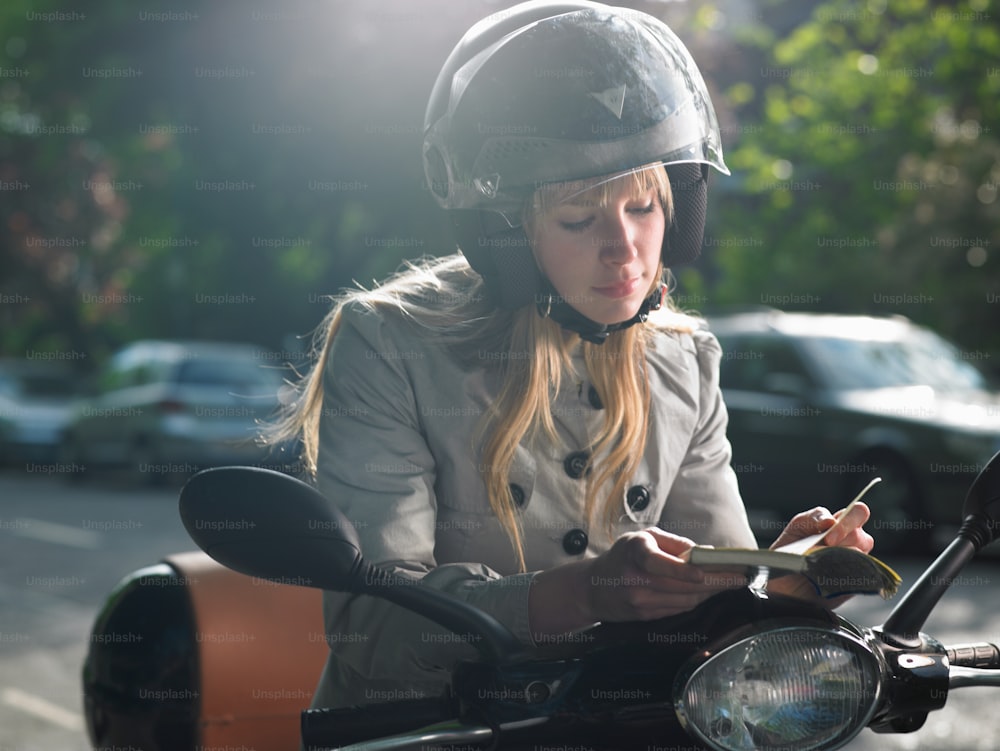 una donna seduta su una moto che scrive su un pezzo di carta