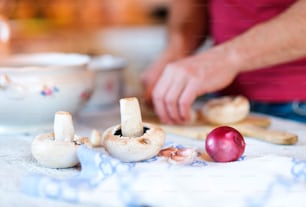 Unrecognizable man in the kitchen cutting mushrooms