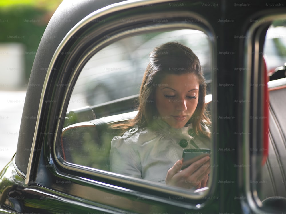a woman sitting in a car looking at her cell phone
