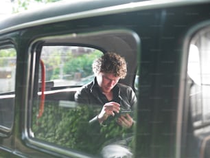 a man sitting in a car looking at his cell phone