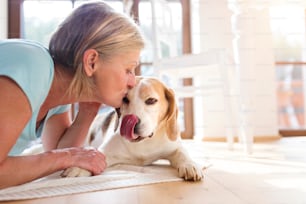 Senior woman with dog inside of her house.