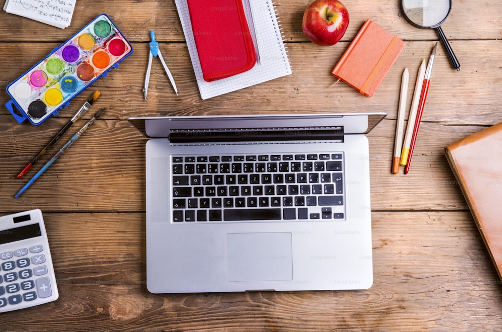 Desk with school supplies. Studio shot on wooden background.