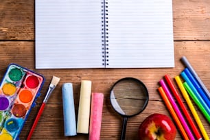 Desk with school supplies. Studio shot on wooden background.