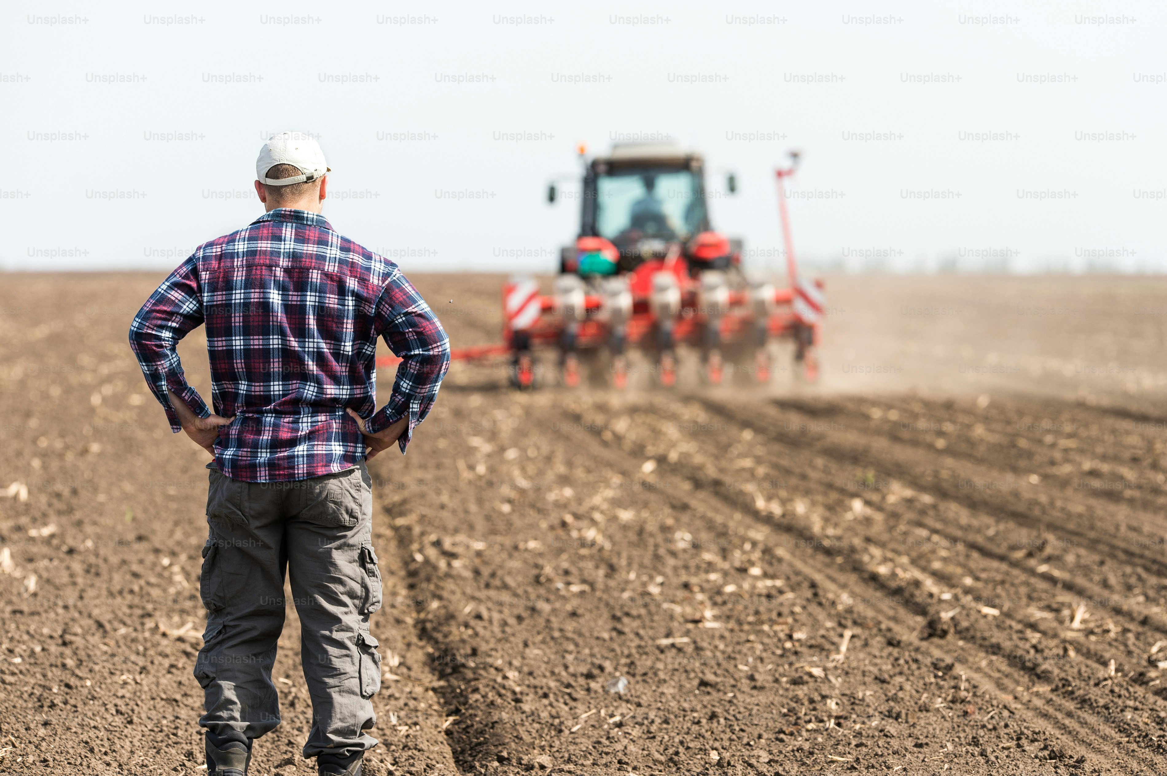 Young farmer on farmland with tractor in background photo – Farm Image ...