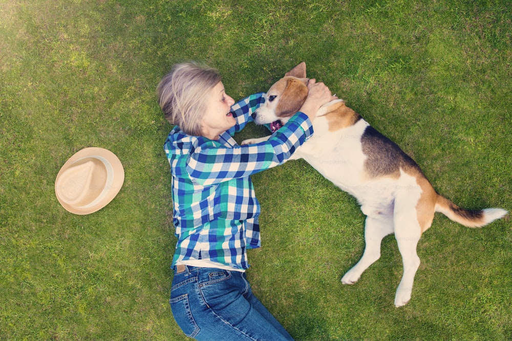 Beautiful senior woman with a dog lying on a grass