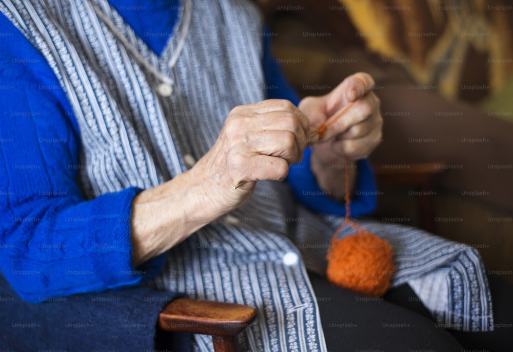 Hände einer älteren Frau beim Stricken mit Wolle und Stricknadeln