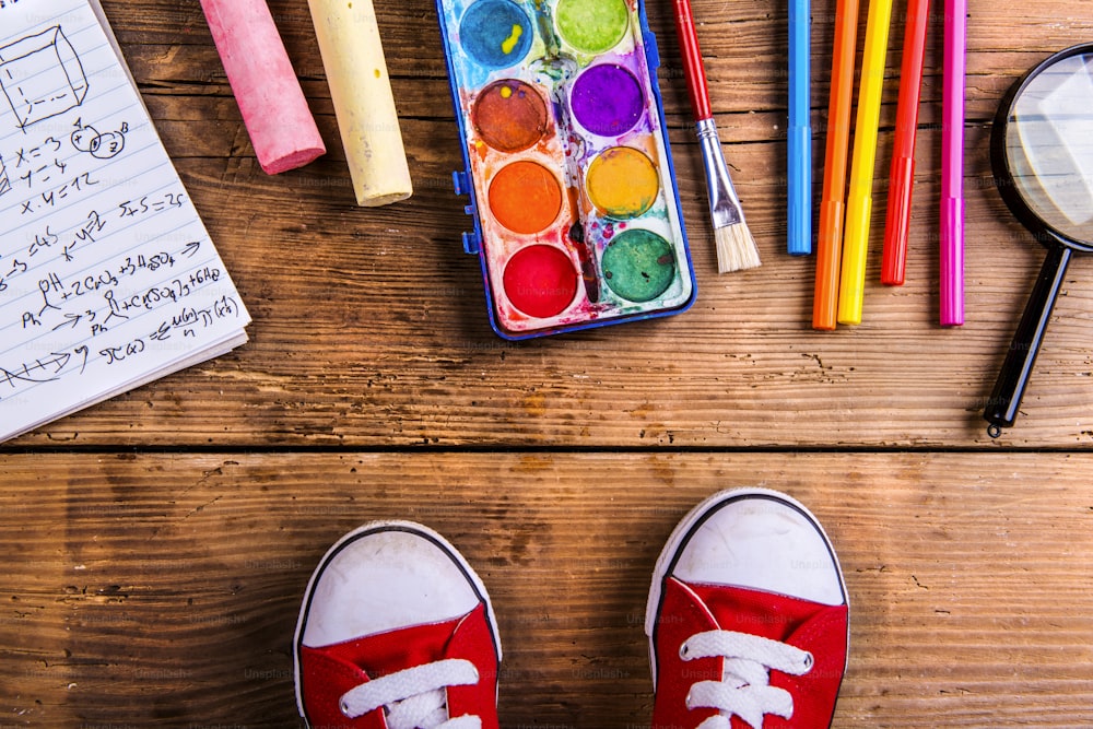 Desk with school supplies. Studio shot on wooden background.