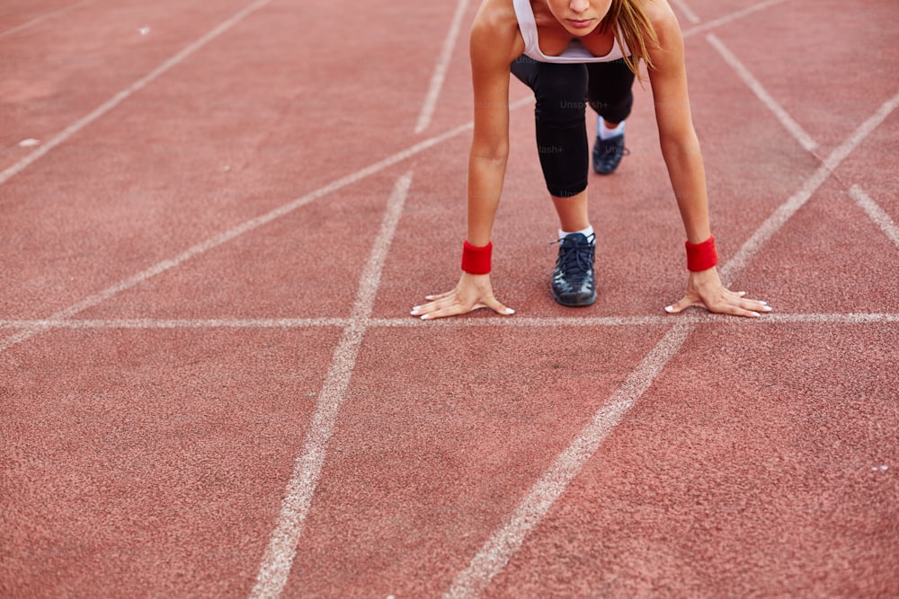 Sporty female on racetrack ready to run