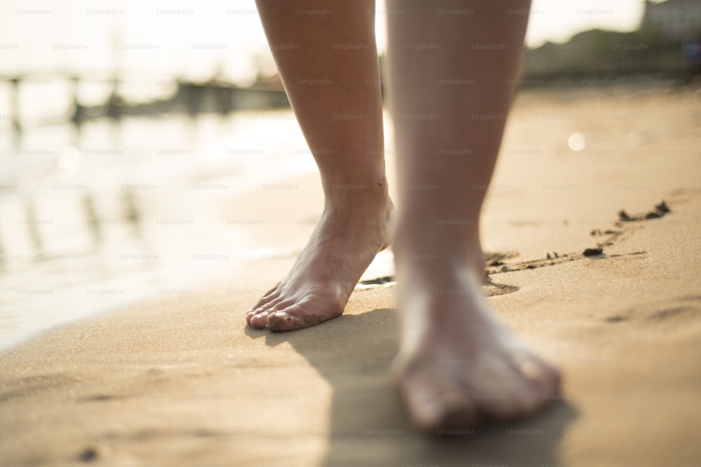 Detalle de los pies descalzos femeninos en la playa soleada