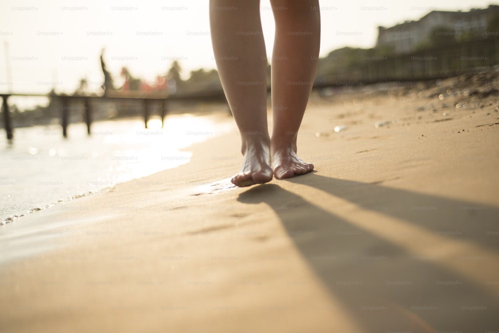 Detalle de los pies descalzos femeninos en la playa soleada