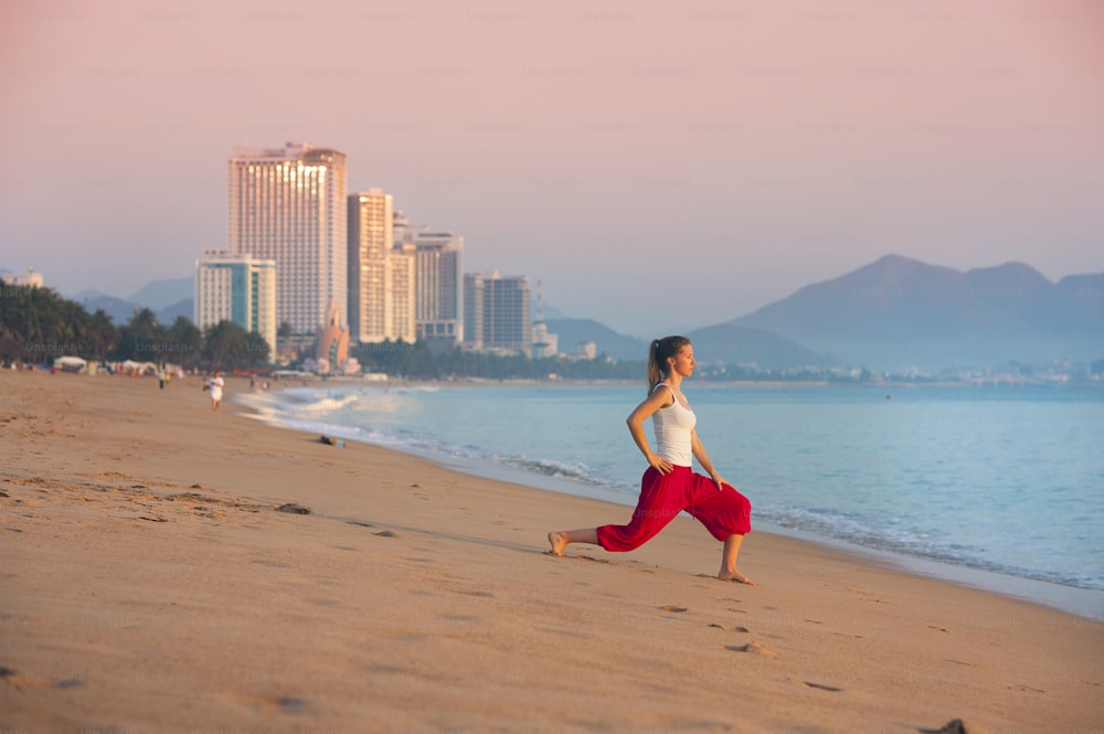 Donna attiva sportiva che si allunga e si esercita sulla spiaggia della città.