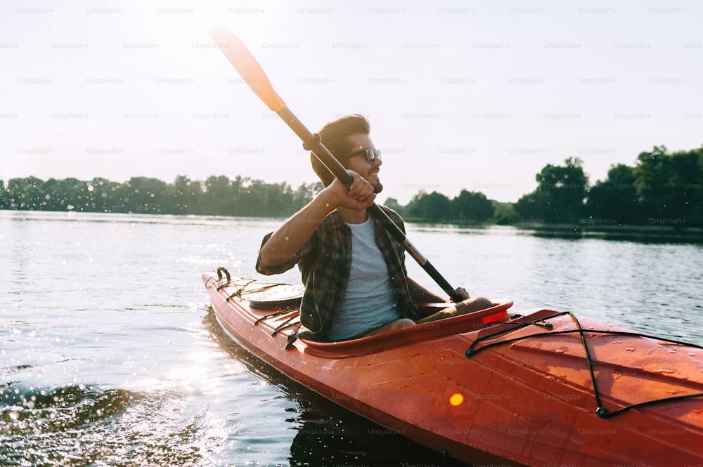 Bel giovane che va in kayak sul lago e sorride