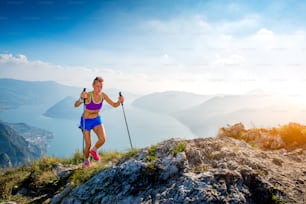 Trail running in the mountains athlete girl with sticks