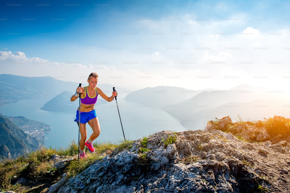 Trail running in the mountains athlete girl with sticks
