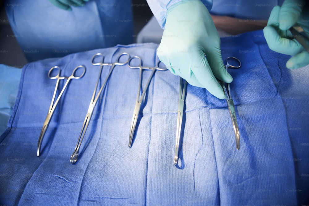 a person with surgical gloves and surgical equipment