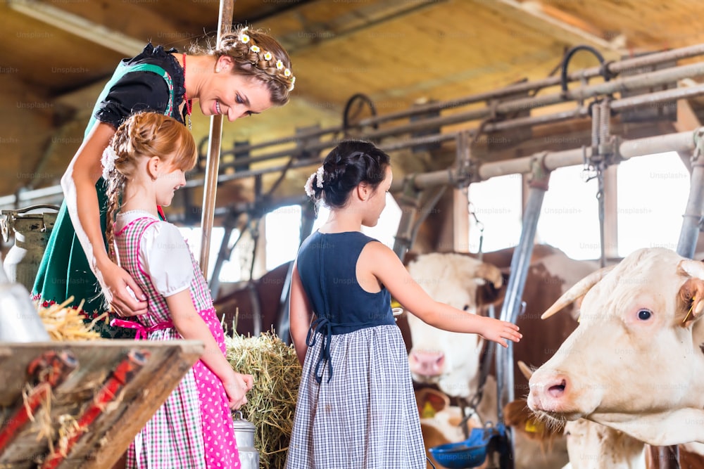 Bavarian mother showing children cows on cow farm