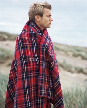 a man wearing a red and black plaid blanket