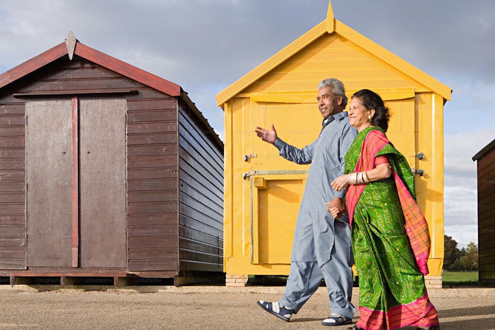 a man and a woman walking in front of a yellow building