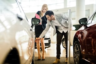 Customer looking at cars at dealership and talking to salesperson