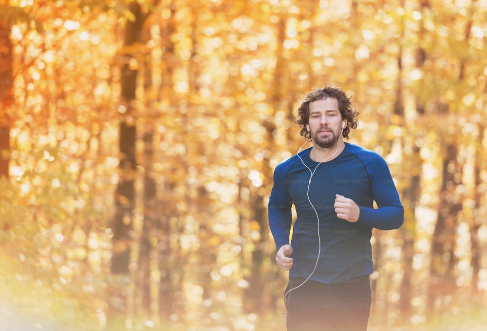 Junger, gutaussehender Läufer draußen in sonniger Herbstnatur