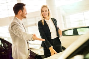 Salesperson showing vehicle to potential customer in dealership