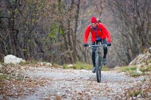 Biker with mountain bike on dirt road in autumn