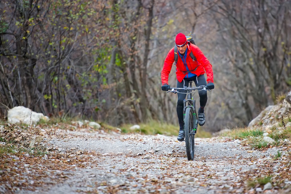 Biker with mountain bike on dirt road in autumn