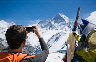Hiker taking photo of Himalayan summit of Machupuchare with smartphone