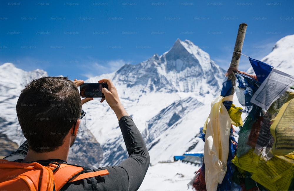 スマートフォンでマチュプチャレのヒマラヤ山頂の写真を撮るハイカー