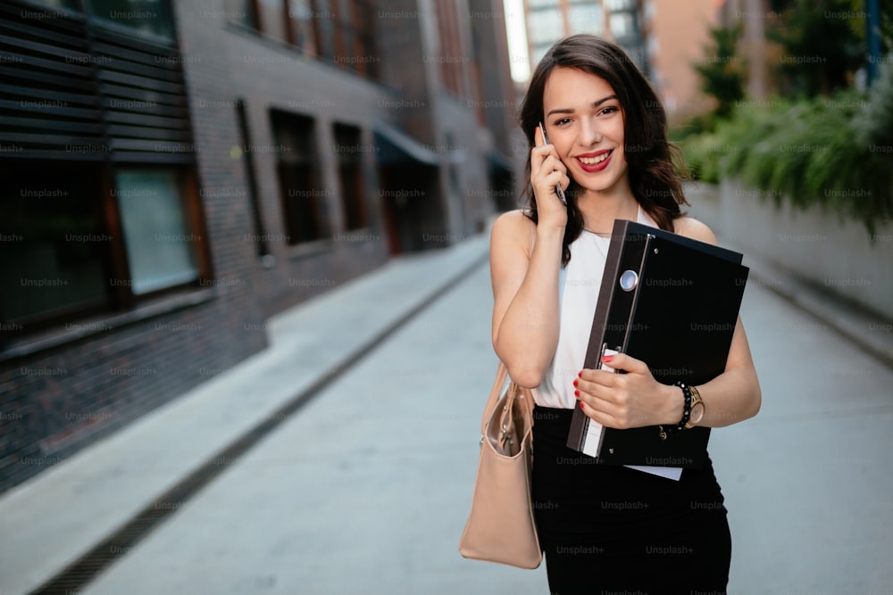 Beautiful businesswoman carrying folders outdoors