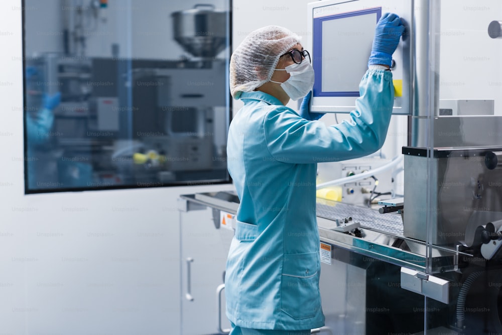 caucasian factory worker in blue lab suit configures control computer