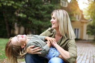 Mother with her daughter playing outdoor. Mother hugging her daughter.