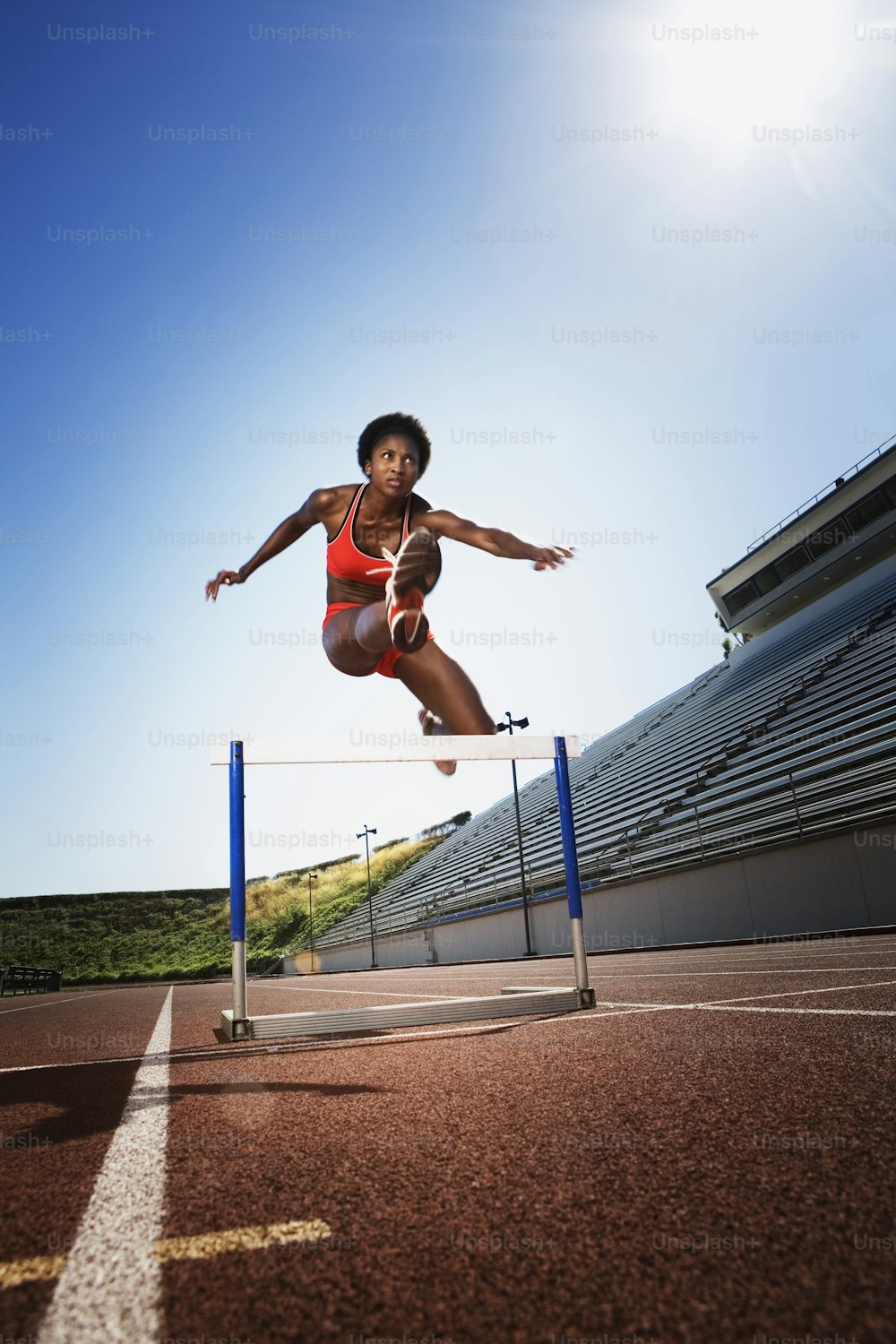 a woman jumping over a hurdle on a track