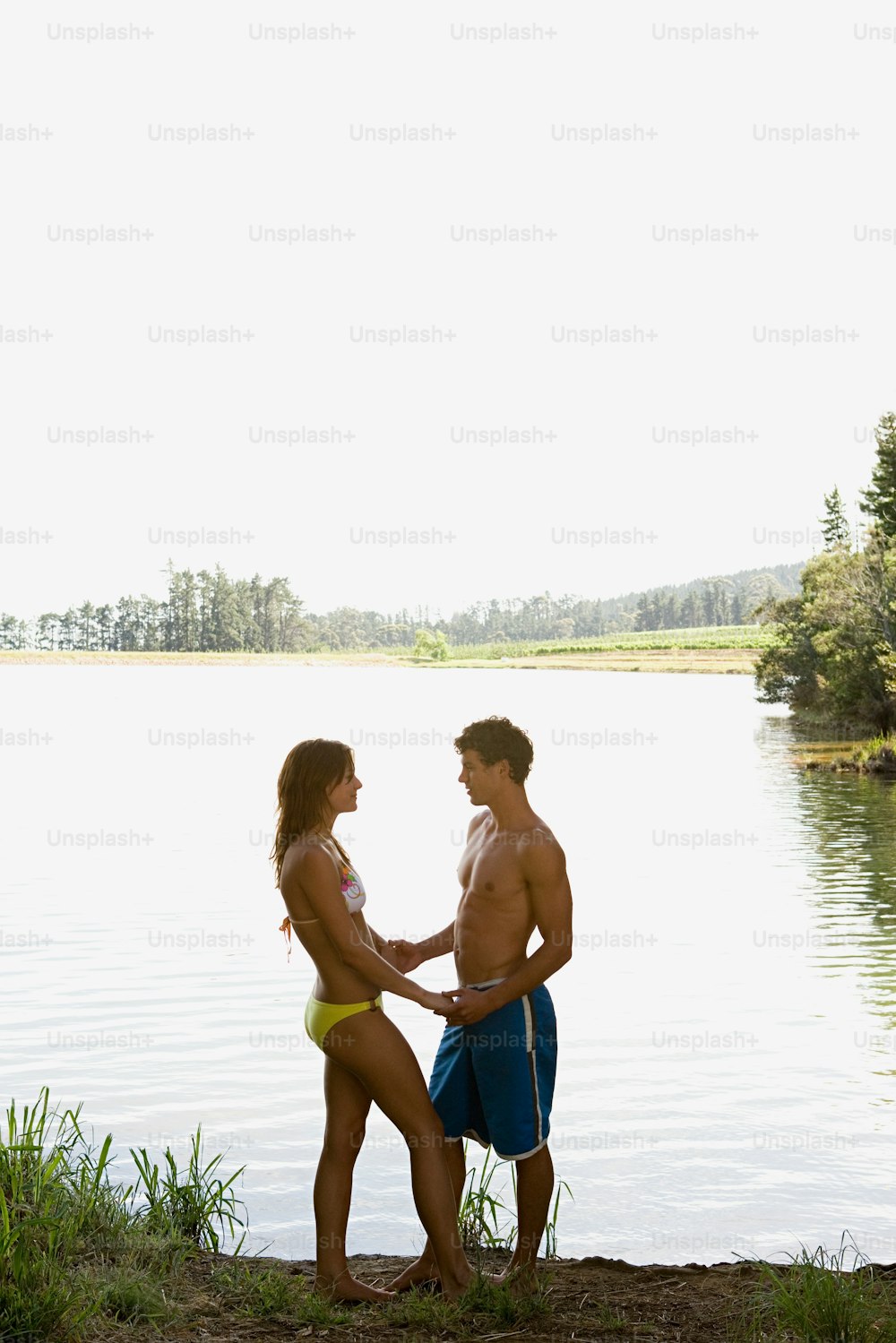 Un hombre y una mujer de pie junto a un cuerpo de agua