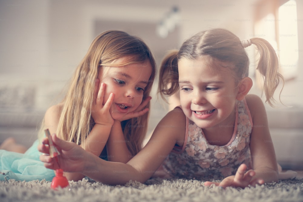 Two little girls painted their nails at home.