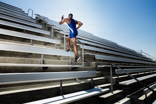 a man in a blue swimsuit is running down a set of bleachers