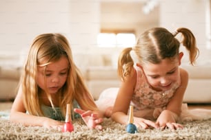 Two little girls painted their nails at home.