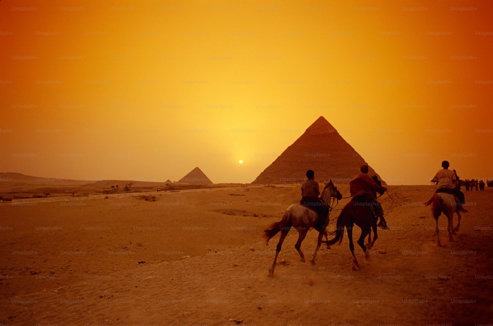 a group of people riding horses in front of the pyramids