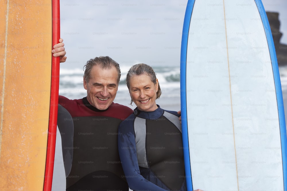a man and a woman standing next to each other holding surfboards