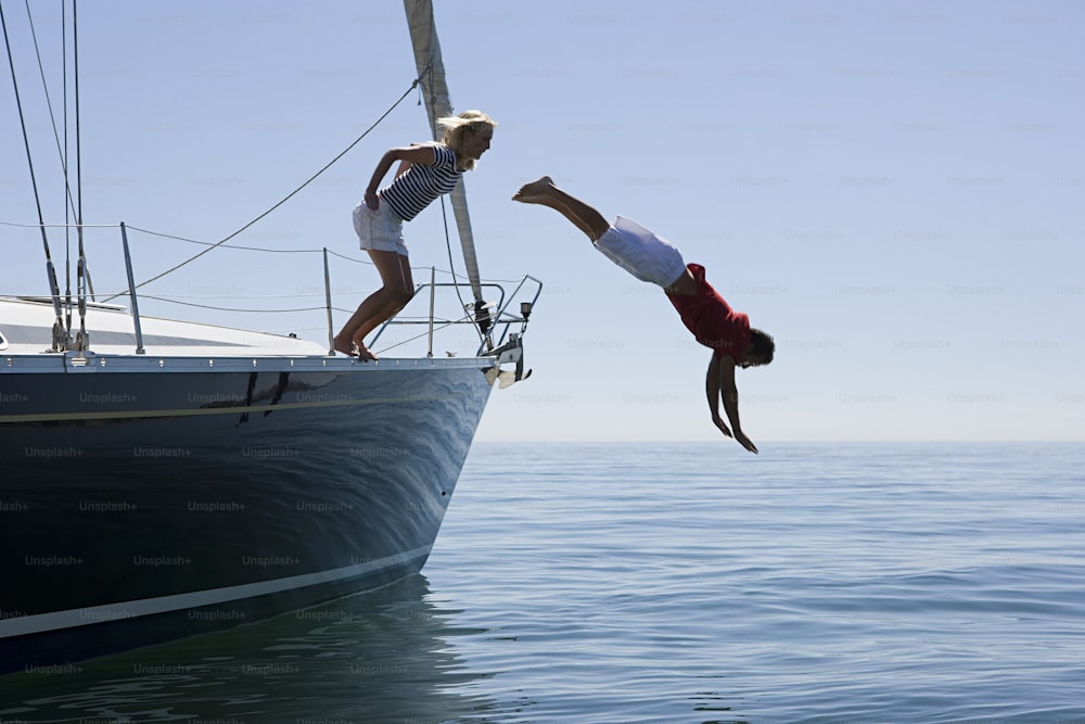 a man and a woman doing a handstand on a boat