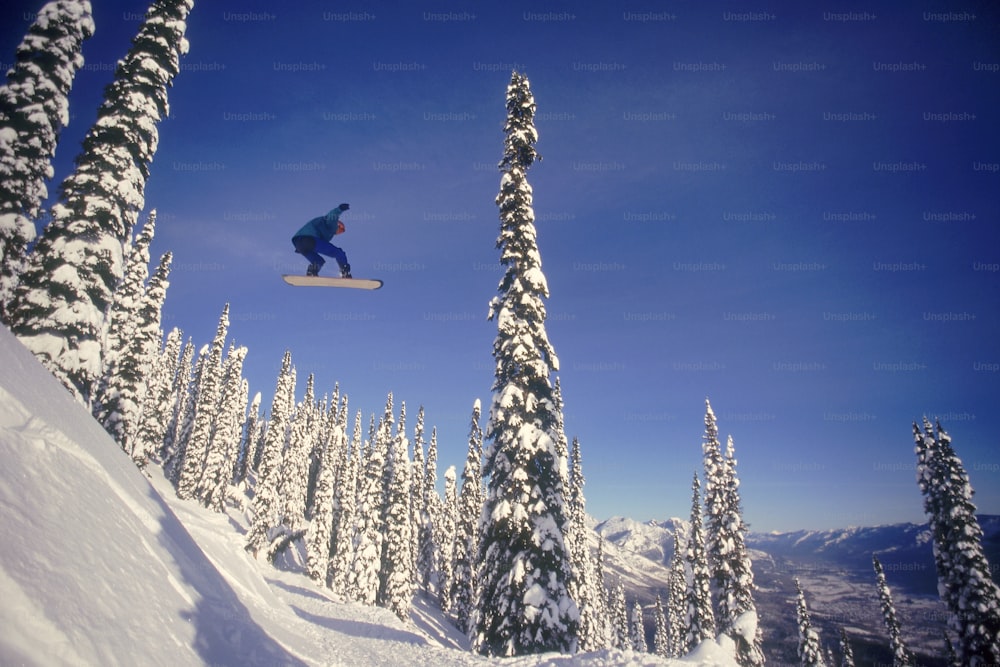 Un hombre volando por el aire mientras monta una tabla de snowboard
