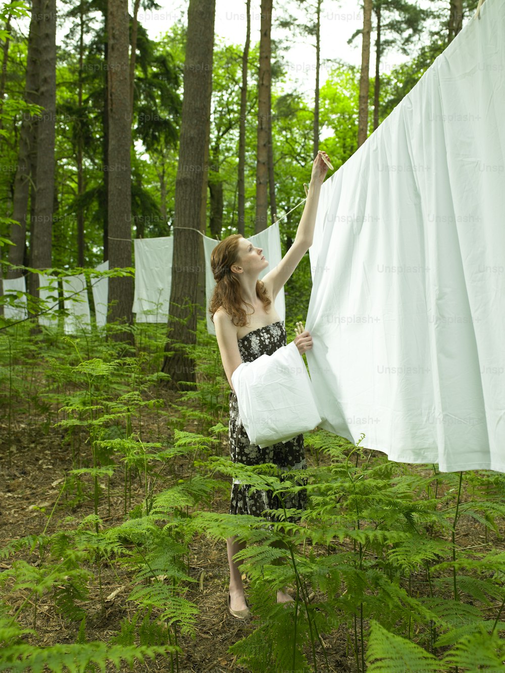 a woman is holding a sheet in the woods