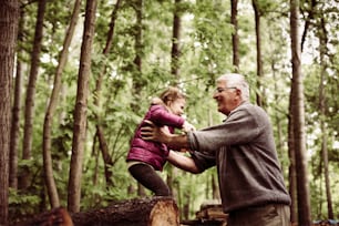公園でおじいちゃんと遊んでいる幸せな子供。